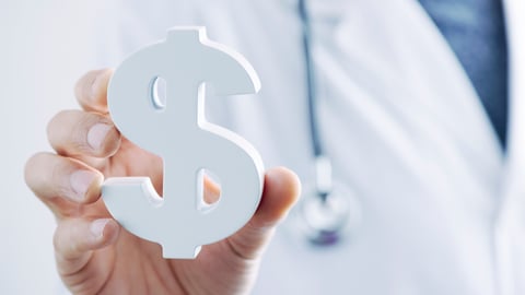 Médecin tenant un sigle dollar en main